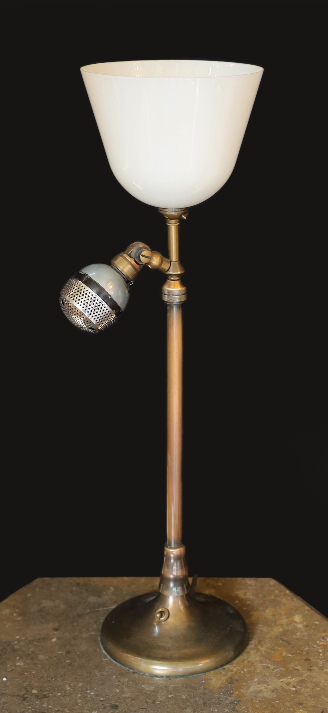 A 1920s BBC microphone converted to a table lamp, with loaded brass base and opaque white glass up lighter shade, height overall 66cm